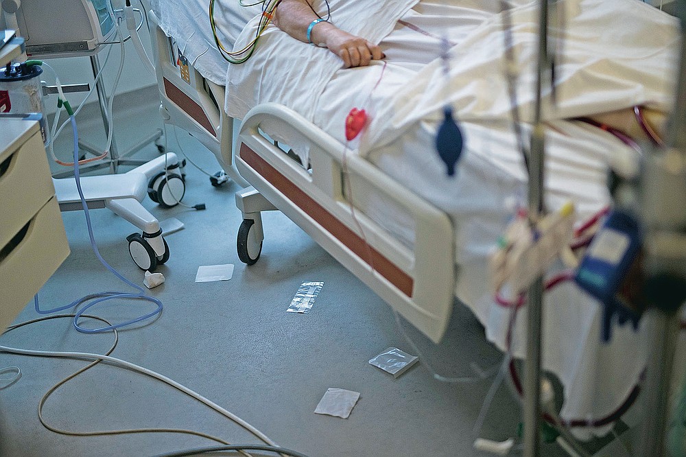 Used surgical cloths and plastic wrappers lie beneath the bed of a 61-year old COVID-19 patient after medical staff provided care in the main ICU of the La Timone hospital in Marseille, southern France, Thursday, Nov. 12, 2020. (AP Photo/Daniel Cole)