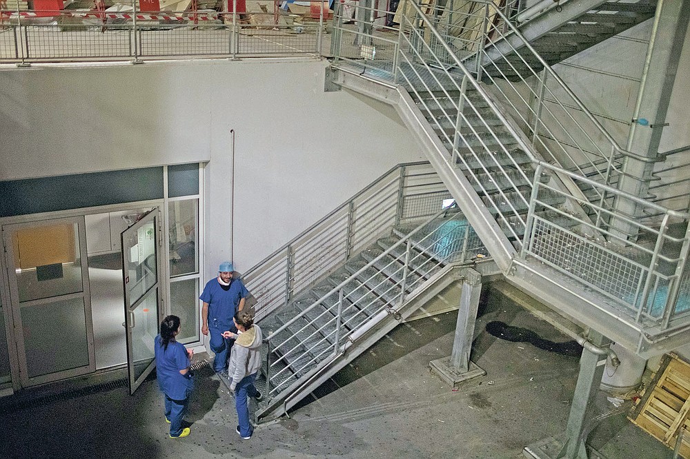 Night shift nurses take a smoke break outside the entrance to the COVID-19 ICU at the La Timone hospital during the early hours of the morning in Marseille, southern France, Friday, Nov. 13, 2020. (AP Photo/Daniel Cole)