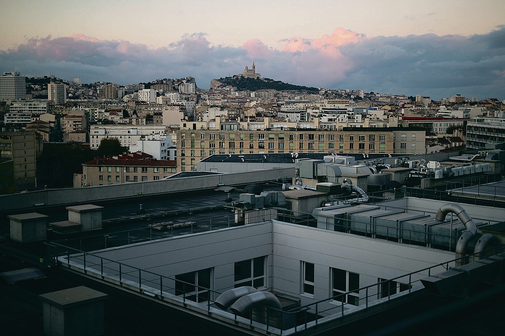 Marseille's Notre-Dame de la Garde basilica is pictured from the roof of the La Timone hospital at sunrise. Friday, Nov. 13, 2020. France is more than two weeks into its second coronavirus lockdown, and intensive care wards have been over 95% capacity for more than 10 days now. Marseille has been submerged with coronavirus cases since September. (AP Photo/Daniel Cole)