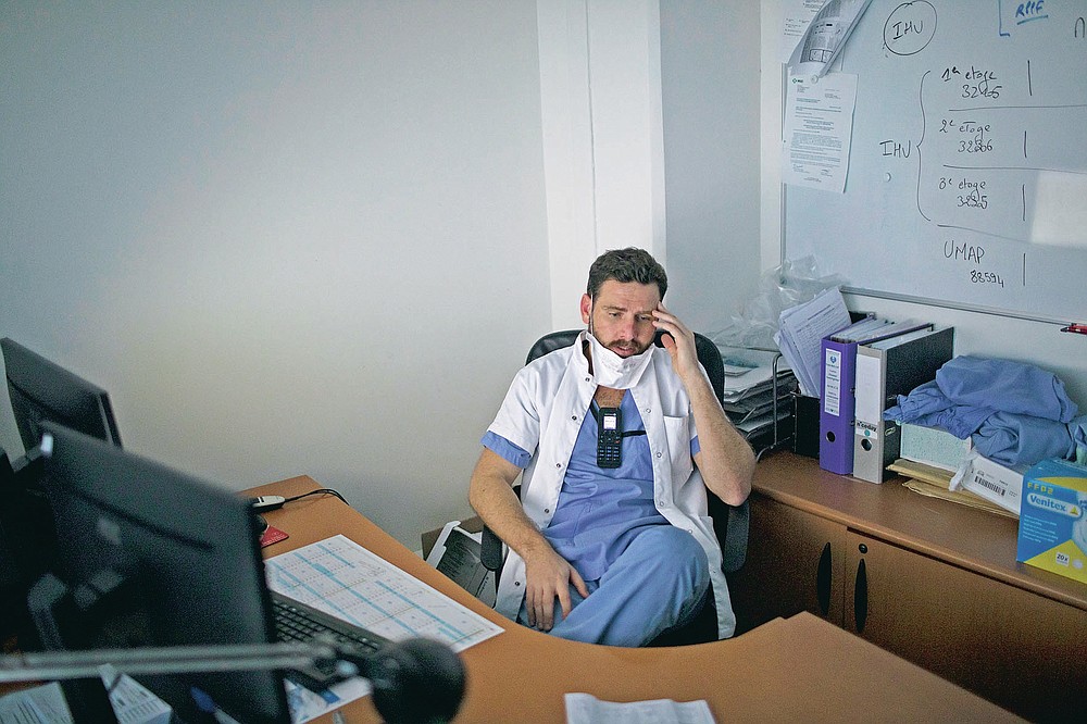 Dr. Julien Carvelli touches his brow after speaking to the relative of a sedated COVID-19 patient who is being treated at the La Timone hospital's ICU in Marseille, southern France, Thursday, Nov. 12, 2020. Dr. Carvelli has to phone families hit by the second wave of the coronavirus with news about their children, husbands, wives. With intensive care wards at over 95% capacity in France for over 10 days, Carvelli makes at least eight of these difficult calls every day. (AP Photo/Daniel Cole)