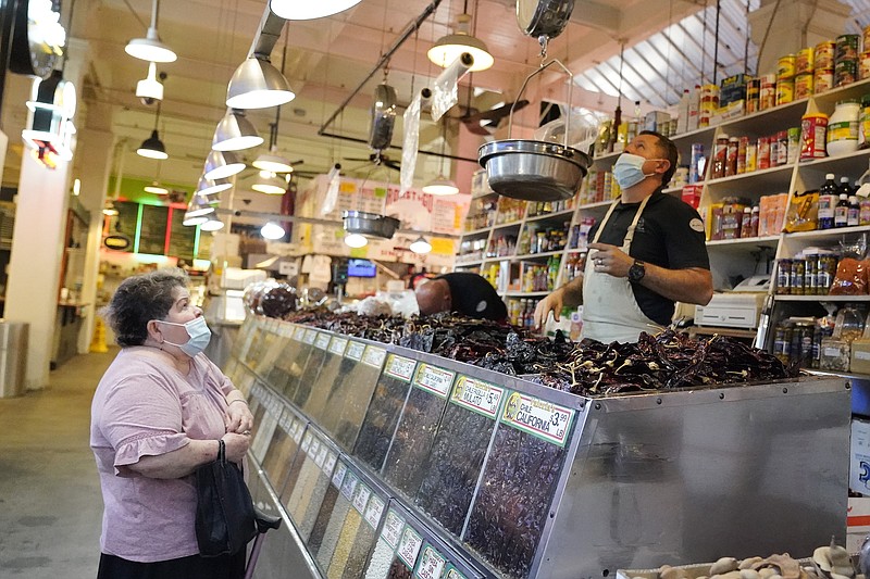 A customer, at left, is tended to at the Grand Central Market Monday, Nov. 16, 2020, in Los Angeles. California Gov. Gavin Newsom announced Monday, Nov. 16, 2020, that due to the rise of COVID-19 cases, Some counties have been moved to the state's most restrictive set of rules. The new rules begin, Tuesday, Nov. 17. (AP Photo/Marcio Jose Sanchez)