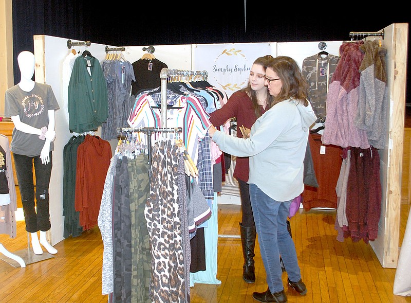File Photo The Siloam Springs Community Building hosted the Jingle and Mingle Holiday Market where businesses set up booths to display their sale items. Two customers are browsing for bargains at Simply Sophie’s booth during Small Business Saturday 2019