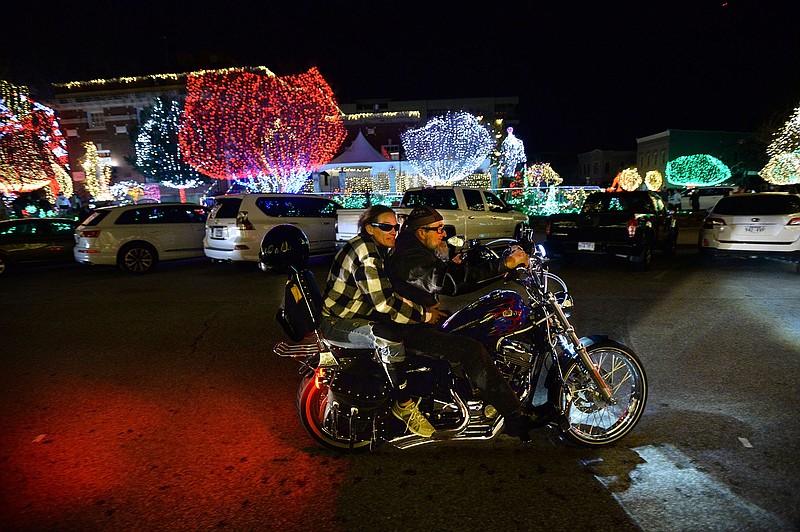 Bob Easley (right) of Fayetteville and friend Brandy Anderson of Siloam Springs ride Friday around the Fayetteville square on Easley's Harley-Davidson Sportster after the annual Lights of the Ozarks display was turned on remotely. This year's ceremony was held online with Mayor Lioneld Jordan flipping a prop switch at the KFSM-TV studio while the lights' activation was streamed simultaneously online. People are encouraged to visit the lights on their own time and avoid congregating in large groups because of the covid-19 pandemic. Visit nwaonline.com/201121Daily/ for today's photo gallery.
(NWA Democrat-Gazette/Andy Shupe) story.lead_photo.caption