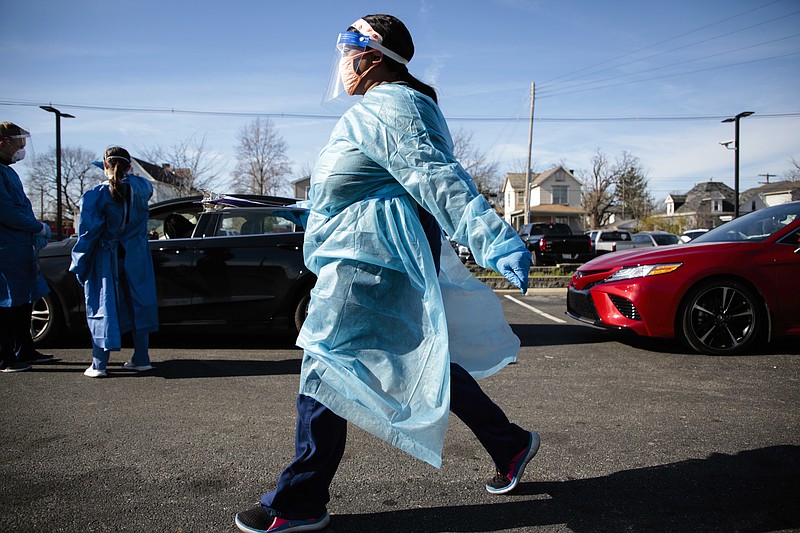 A nurse carries a COVID-19 test back for processing Thursday at PrimaryOne Health in Columbus, Ohio. The surge of coronavirus is taking an increasingly grim toll across the United States, even as of a vaccine appears close at hand. - Joshua A. Bickel/The Columbus Dispatch via AP story.lead_photo.caption