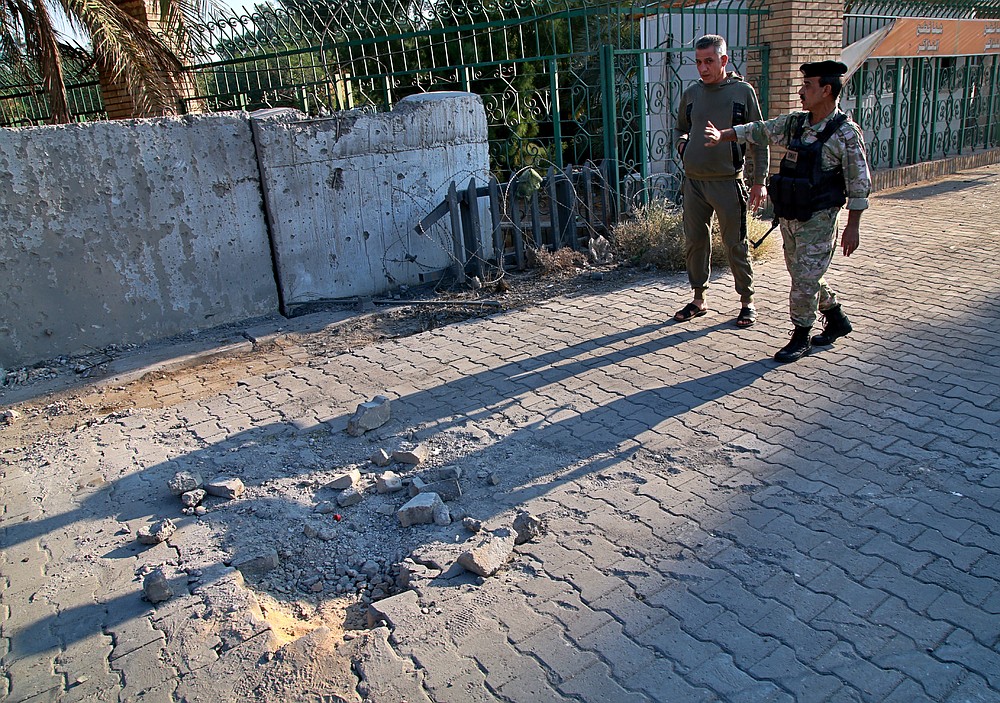 Security forces inspect the scene of the rocket attack at the gate of al-Zawra public park in Baghdad, Iraq, Wednesday, Nov. 18, 2020. Rockets struck Iraq's capital on Tuesday with four landing inside the heavily fortified Green Zone, Iraq's military said, killing a child and wounding at least five people, signaling an end to an informal truce announced by Iran-backed militias in October. (AP Photo/Khalid Mohammed)