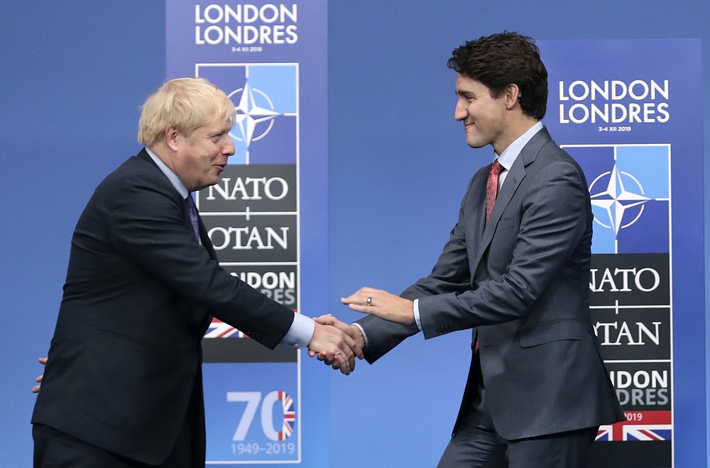 FILE - In this Wednesday, Dec. 4, 2019 file photo, British Prime Minister Boris Johnson, left, welcomes Canadian Prime Minister Justin Trudeau during official arrivals for a NATO leaders meeting at The Grove hotel and resort in Watford, Hertfordshire, England. The U.K. has signed an interim trade deal with Canada _ a rollover measure meant to cement the trading relationship as the government prepares of life outside the European Union. While Britain formally withdrew from the EU in January, it continues to trade with other countries under the bloc’s umbrella during a transition period that is scheduled to end Dec. 31. (AP Photo/Francisco Seco, File)
