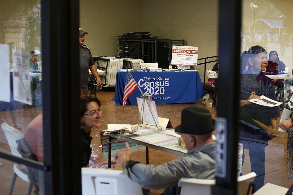 FILE - In this Feb. 8, 2020, file photo, people volunteer to get people registered to vote and a booth offering employment for the upcoming 2020 census stands in the background, during the celebration of the town's 45th year since it was incorporated, in Guadalupe, Ariz. Today, nearly a third of Guadalupe's 6,500 residents say they are Native American and about 75% of all races identify as Hispanic. (AP Photo/Dario Lopez-MIlls, File)