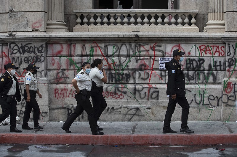Police officers patrol in front of the Congress building that was damaged during protests in Guatemala City, Sunday, Nov. 22, 2020. Protesters broke into the building and set it partially on fire amid growing demonstrations against President Alejandro Giammattei and the legislature for approving a controversial budget that cut educational and health spending. (AP Photo/Moises Castillo)