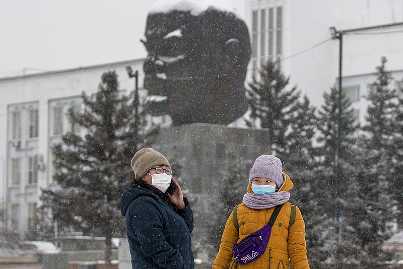 Two women wearing face masks to protect against coronavirus stand in front of a monument of Vladimir Lenin in Ulan-Ude, the regional capital of Buryatia, a region near the Russia-Mongolia border, Russia, Friday, Nov. 20, 2020. Russia’s health care system has been under severe strain in recent weeks, as a resurgence of the coronavirus pandemic has swept the country. (AP Photo/Anna Ogorodnik)
