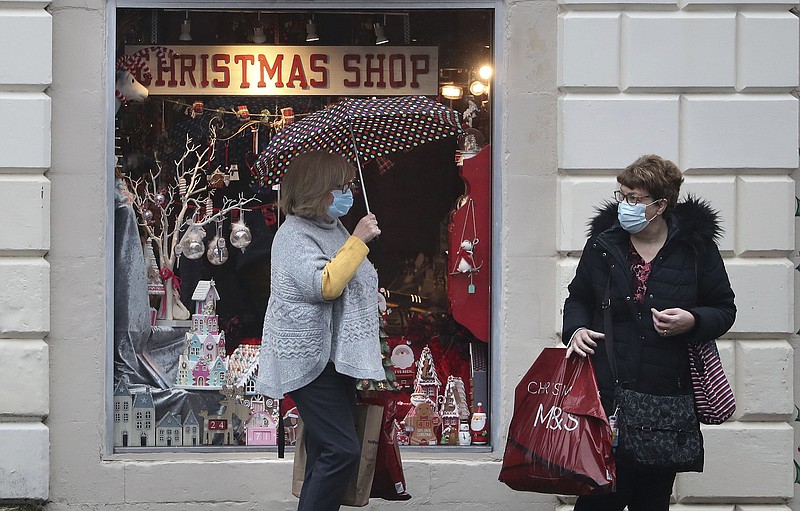 People wearing face coverings outside a Christmas Shop in Stirling, Scotland, Friday Nov. 20, 2020. This shop will close later Friday along with other non-essential shops, bars, restaurants, hairdressers and visitor attractions whilst schools remain open, due to the latest government restrictions imposed to slow the spread of coronavirus. (Andrew Milligan/PA via AP)