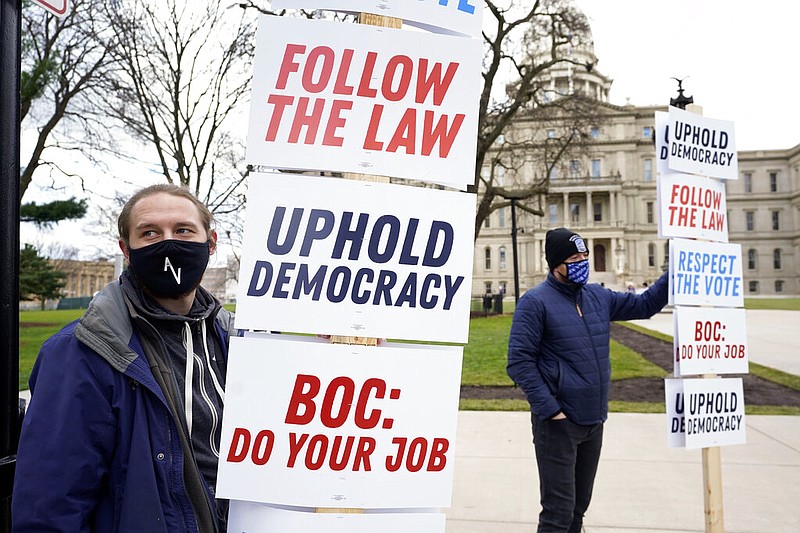 Joscha Weese, left, stands outside the Capitol building during a rally in Lansing, Mich., Saturday, Nov. 14, 2020. Michigan's elections board is scheduled to meet to certify the state's presidential election results Monday. (AP Photo/Paul Sancya)