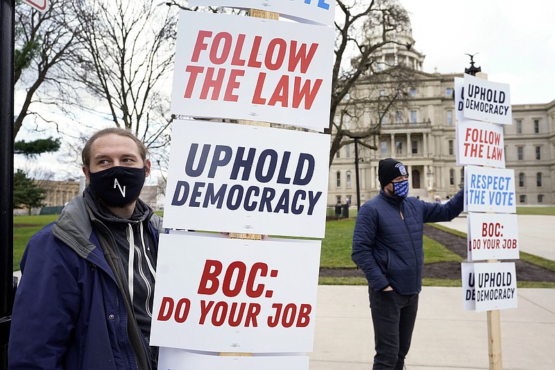 Joscha Weese, left, stands outside the Capitol building during a rally in Lansing, Mich., Saturday, Nov. 14, 2020. Michigan's elections board is scheduled to meet to certify the state's presidential election results Monday. (AP Photo/Paul Sancya)