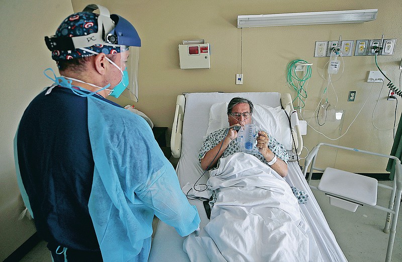 Registered Nurse Daniel Corral works with a COVID-19 patient at the El Paso Long Term Acute Care Hospital, Friday, Nov. 6, 2020, in El Paso, Texas. The relentless war against a deadly, invisible enemy was out of sight to all but those working its front lines. (Mark Lambie/The El Paso Times via AP)