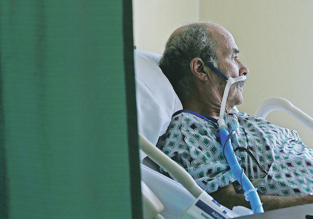 A COVID-19 patient sits in his hospital bed at the El Paso Long Term Acute Care Hospital, Friday, Nov. 6, 2020, in central El Paso, Texas. El Paso is seeing a spike in coronavirus cases. (Mark Lambie/The El Paso Times via AP)