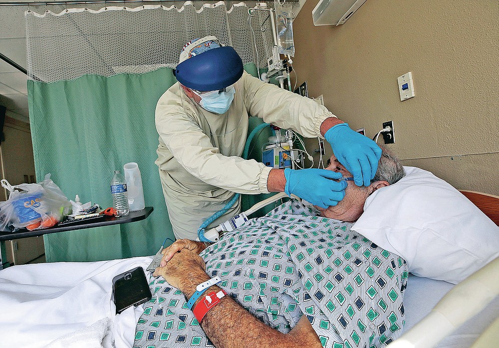 Respiratory Therapist Vidal Perea checks the oxygen on a COVID-19 patient at the El Paso Long Term Acute Care Hospital, Friday, Nov. 6, 2020, in central El Paso, Texas. Hundreds of health care workers have flown into El Paso to pick up shifts from exhausted doctors and nurses and to staff tent hospitals erected in parking lots.(Mark Lambie/The El Paso Times via AP)