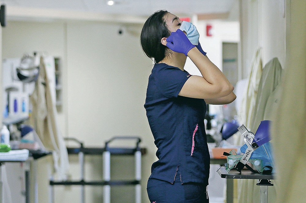 Certified Nursing Assistant Angelica Corral constantly changes her personal protective equipment (PPE) as she travels from room to room at the El Paso Long Term Acute Care hospital, Friday, Nov. 6, 2020, in central El Paso, Texas. Across the city, more than 1,000 people per day are testing positive and the city’s major hospitals are overrun with severely ill and dying El Pasoans. (Mark Lambie/The El Paso Times via AP)