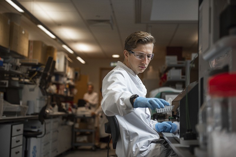 In this undated photo issued by the University of Oxford, a researcher in a laboratory at the Jenner Institute in Oxford, England, works on the coronavirus vaccine developed by AstraZeneca and Oxford University. Pharmaceutical company AstraZeneca said Monday Nov. 23, 2020, that late-stage trials showed its coronavirus vaccine was up to 90% effective, giving public health officials hope they may soon have access to a vaccine that is cheaper and easier to distribute than some of its rivals. (University of Oxford/John Cairns via AP)