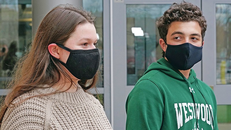 While wearing protective masks due to the COVID-19 outbreak, Lucy Vitali, who portrays Juliet, left, stands with Alex Mansour, who portrays Romeo, outside the auditorium after working on their virtual performance of Shakespeare's "Romeo and Juliet," at Westwood, Mass. High School, Monday, Nov. 16, 2020, in Westwood. The production, which would usually be presented onstage, shifted to a virtual audience due to the pandemic. (AP Photo/Charles Krupa)