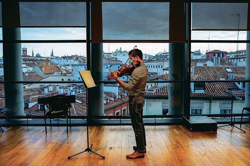 A musician in a face mask plays the violin at a rehearsal at the Teatro Real in Madrid, Spain, Friday, Nov. 13, 2020. The theater is one of the few major opera houses that have reopened during the pandemic, although to smaller audiences.  (AP Photo/Bernat Armangue)