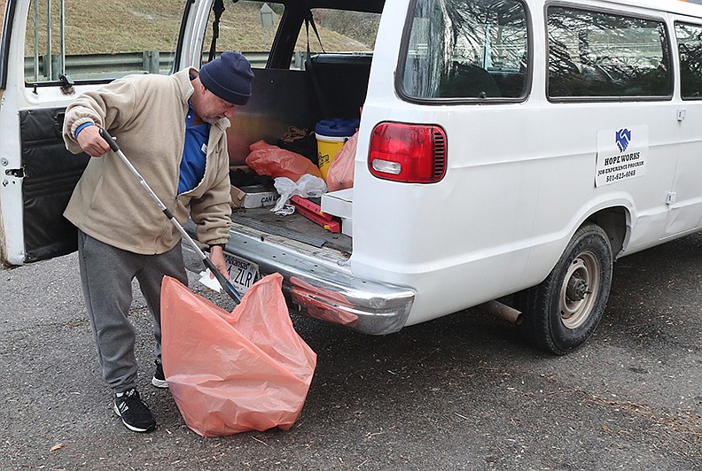 Hope Works Director David Cook looks through some trash on Malvern Avenue Tuesday. - Photo by Richard Rasmussen of The Sentinel-Record
