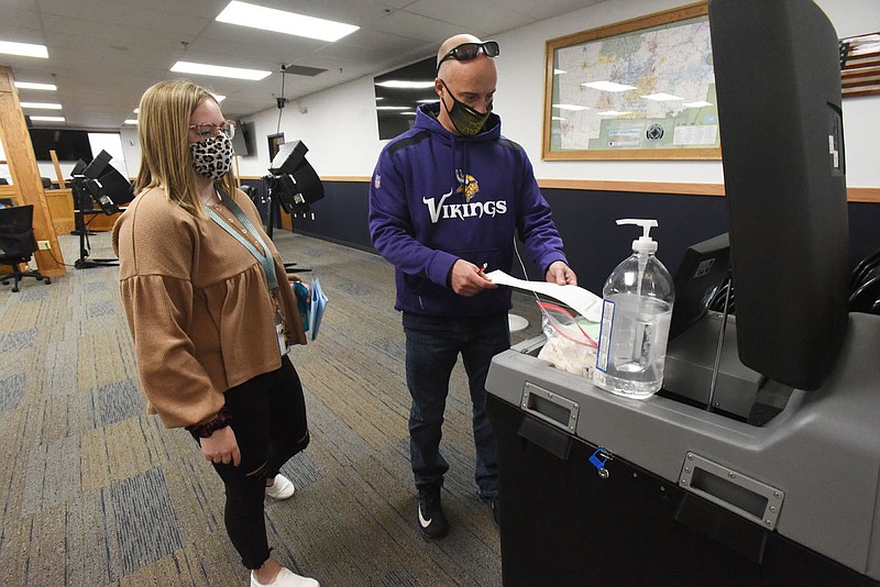 Kelsi Crawford with the Benton County Clerk's Office helps Josh Carlson of Bentonville cast his ballot on Wednesday Nov. 25 2020 during early voting for the runoff election at the Benton County Administration building. (NWA Democrat-Gazette/Flip Putthoff)