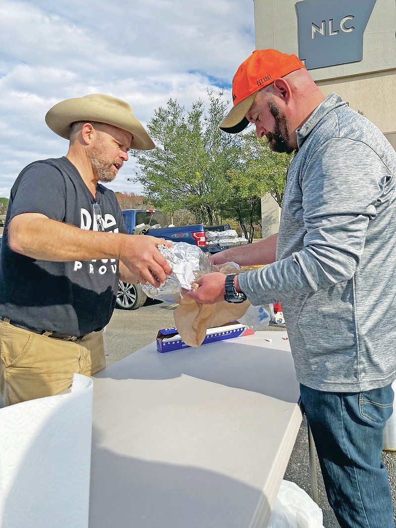 The Rev. Matt Mosler, left, pastor at New Life Church in Pine Bluff, and Bryan Paul, a church member, load a just-fried turkey into a bag on Tuesday to get it ready to be given away. (Pine Bluff Commercial/Byron Tate)
