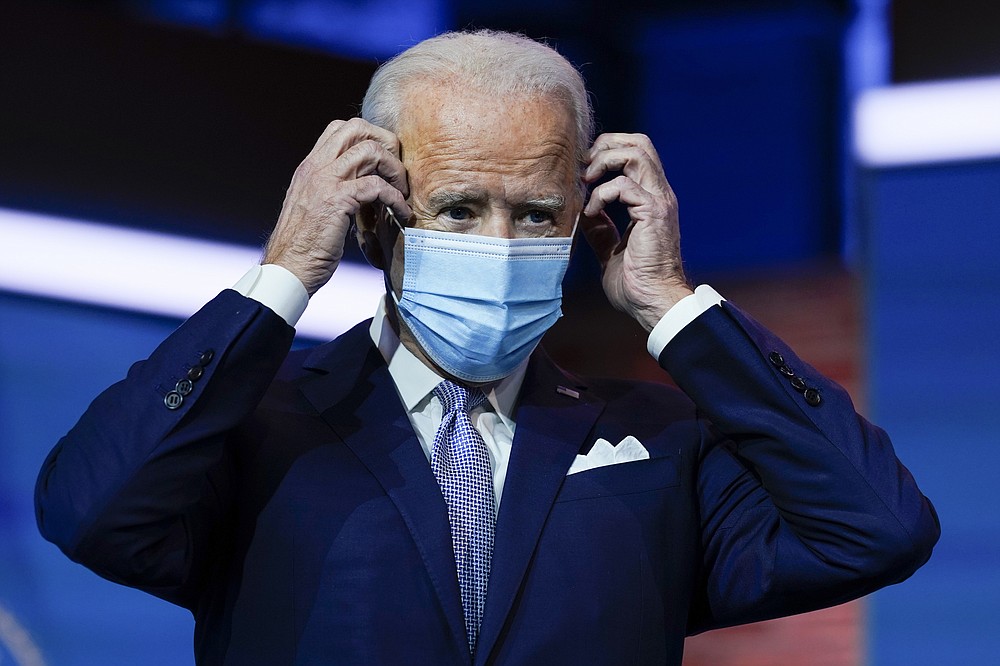 FILE - In this Nov. 24, 2020, file photo President-elect Joe Biden puts on his face mask after introducing nominees and appointees to key national security and foreign policy posts at The Queen theater in Wilmington, Del. Congress is bracing for Biden to move beyond the Trump administration’s state-by-state approach to the COVID-19 crisis and build out a national strategy to fight the pandemic and distribute the eventual vaccine.(AP Photo/Carolyn Kaster, File)