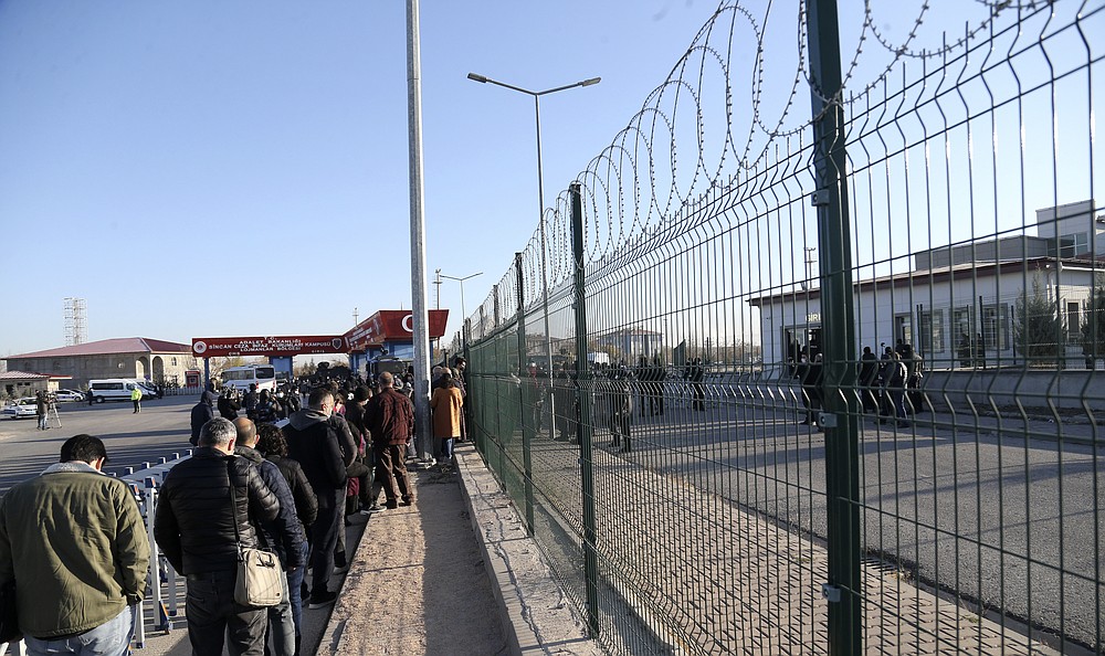 People wait outside a courthouse before the trial of 475 defendants, including generals and fighter jet pilots, in Sincan, Ankara, Turkey, Thursday, Nov. 26, 2020. A Turkish court sentenced several military and civilian personnel at an air base to life prison sentences Thursday, proclaiming them guilty of involvement in a failed coup attempt in 2016, the state-run news agency reported. (AP Photo)