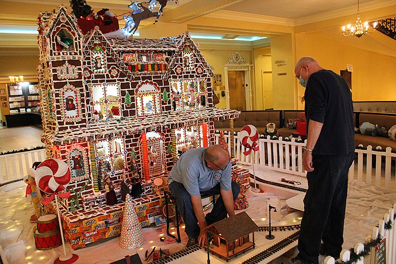 Murph Tetley, left, leader of the Greater Hot Springs Garden Railway Society, and his brother-in-law Larry Gray put the last piece of track down for the model train in the lobby of the Arlington. While the hotel building a gingerbread house dates back to the 1980s, this is only the second year that it has featured a model train. - Photo by Tanner Newton of The Sentinel-Record