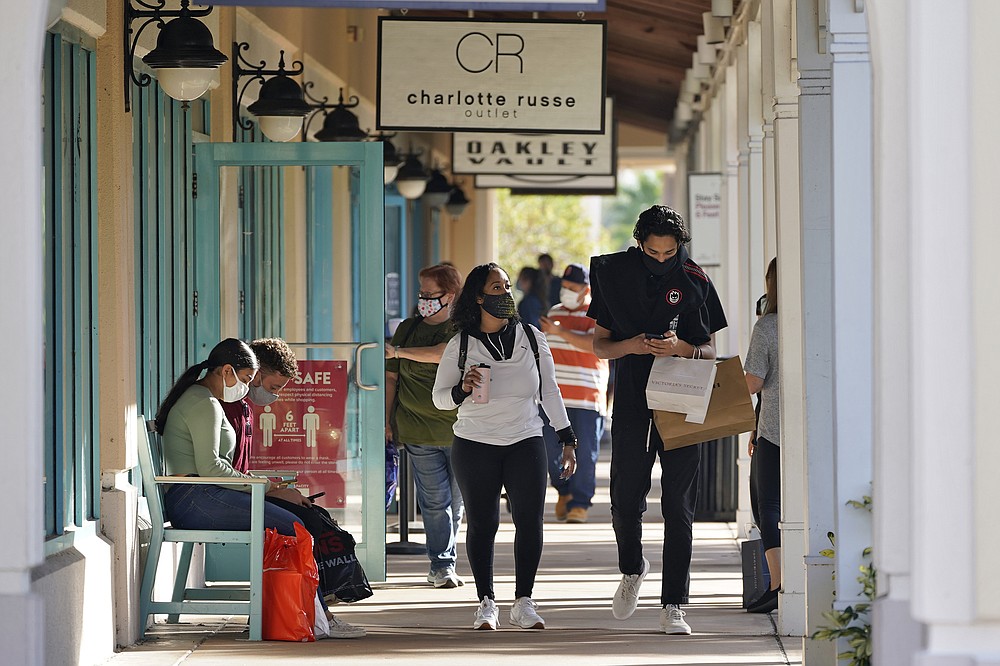 Shoppers wear protective face masks as they look for Black Friday deals at the Ellenton Premium Outlet stores Friday, Nov. 27, 2020, in Ellenton, Fla. Attendance at the mall was down in an attempt to avoid spreading the corona virus. (AP Photo/Chris O'Meara)