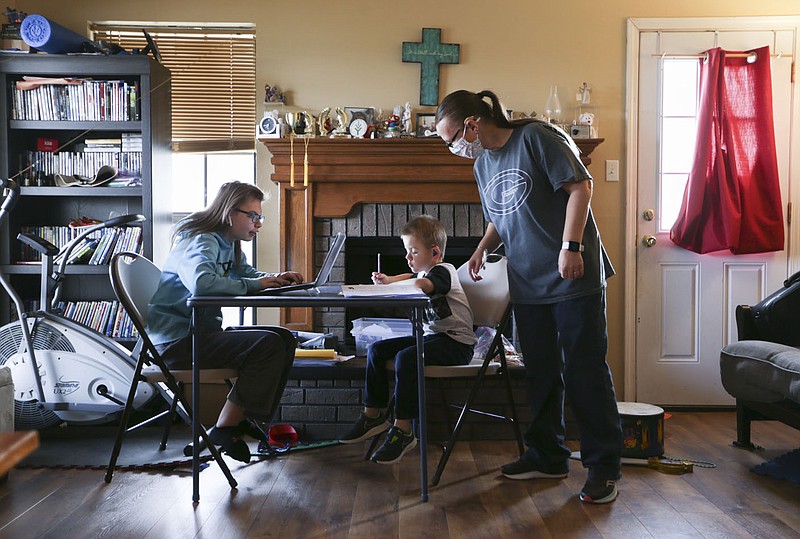 Carol Andrews (right) helps Colton Andrews, 6, with his school work Nov. 20 as Christina Andrews, 13, works on her school work at their home in Greenwood. Greenwood shifted to all-virtual instruction for the latter part of November including Colton and Christina. Colton is a special-education student with a learning disability and Christina has ADHD. Check out nwaonline.com/201129Daily/ for today's photo gallery. 
(NWA Democrat-Gazette/Charlie Kaijo)