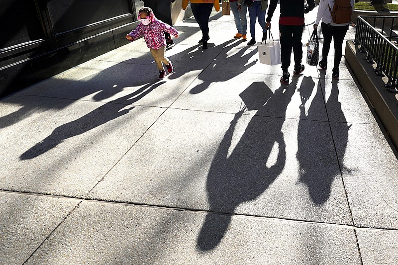 Shoppers cast their shadows Saturday as they walk Chicago's famed Magnificent Mile shopping district while a child runs by. - AP Photo/Charles Rex Arbogast