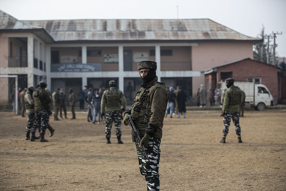 Indian soldiers stand guard outside a polling station during the first phase of District Development Councils election on the outskirts of Srinagar, Indian controlled Kashmir, Saturday, Nov. 28, 2020. Thousands of people in Indian-controlled Kashmir voted Saturday amid tight security and freezing cold temperatures in the first phase of local elections, the first since New Delhi revoked the disputed region's semiautonomous status. (AP Photo/Mukhtar Khan)