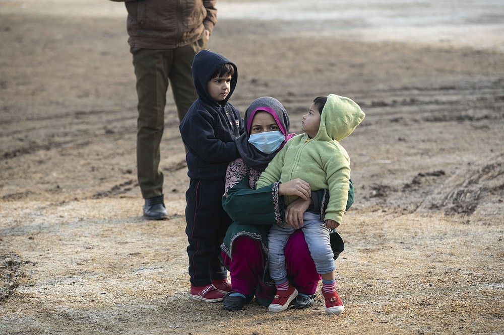 A Kashmiris waits with children outside a polling booth during the first phase of District Development Councils election on the outskirts of Srinagar, Indian controlled Kashmir, Saturday, Nov. 28, 2020. Thousands of people in Indian-controlled Kashmir voted Saturday amid tight security and freezing cold temperatures in the first phase of local elections, the first since New Delhi revoked the disputed region's semiautonomous status. (AP Photo/Mukhtar Khan)