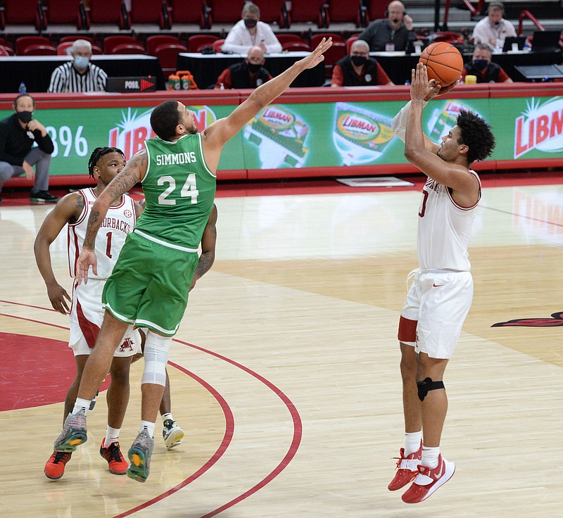 Arkansas forward Justin Smith, right, leaps to score over North Texas forward Zachary Simmons (24) during the first half of Saturday's game in Bud Walton Arena. - Photo by Andy Shupe of NWA Democrat-Gazette