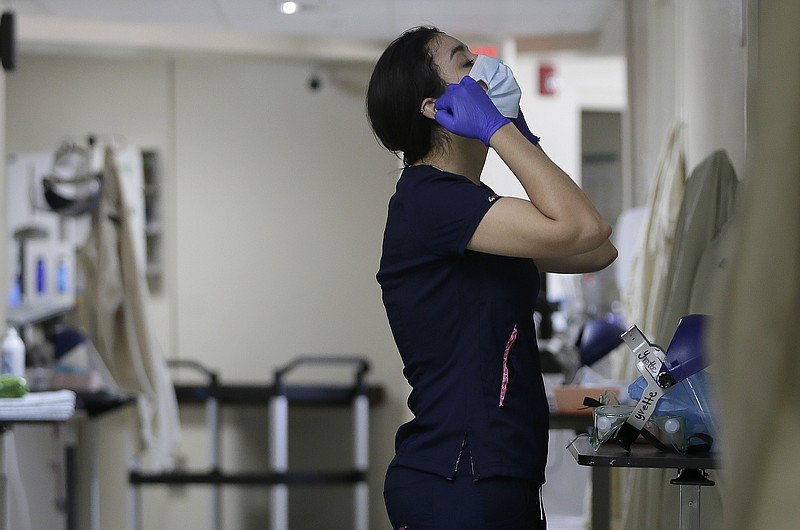 FILE - Certified Nursing Assistant Angelica Corral changes her personal protective equipment (PPE) as she travels from room to room at the El Paso Long Term Acute Care hospital, Friday, Nov. 6, 2020, in central El Paso, Texas.  Faulting inaction in Washington, governors and state lawmakers are racing to get needed pandemic relief to small businesses, the unemployed, renters and others affected by the widening coronavirus outbreak. In some cases, they are figuring out how to spend the last of a federal relief package passed in the spring as an end-of-year deadline approaches and the current COVID-19 surge threatens their economies once again.  (Mark Lambie/The El Paso Times via AP)