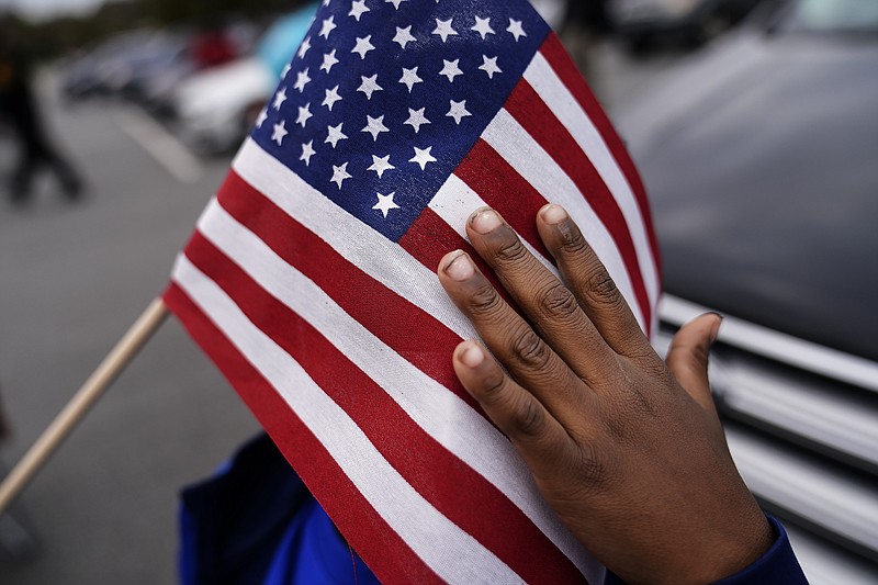 In this Nov. 15 fie photo, a young child holds an American flag as Georgia Democratic candidate for U.S. Senate Raphael Warnock speaks during a campaign rally in Marietta, Ga. - AP Photo/Brynn Anderson