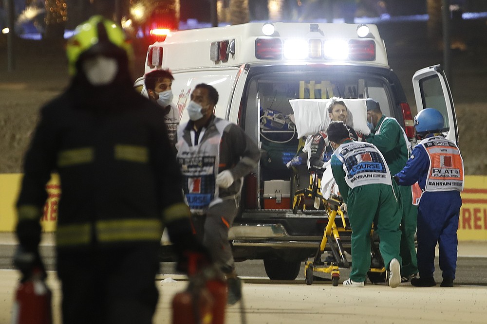 Haas driver Romain Grosjean of France is helped by medical staff after he crashed his car during the Formula One race in Bahrain International Circuit in Sakhir, Bahrain, Sunday, Nov. 29, 2020. (Hamad Mohammed, Pool via AP)