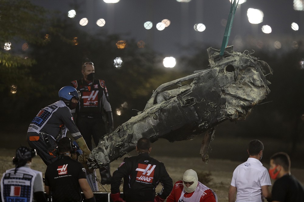 A part of Haas driver Romain Grosjean's car is taken after the crash at the start of the Formula One Bahrain Grand Prix in Sakhir, Bahrain, Sunday, Nov. 29, 2020. (Tolga Bozoglu, Pool via AP)