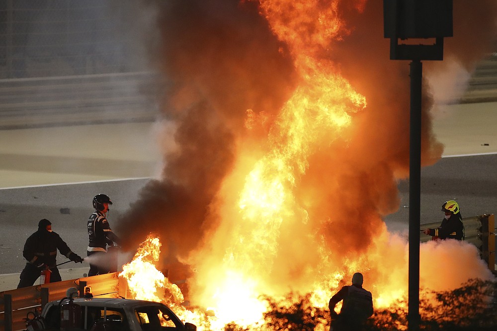 Staff extinguish flames from Haas driver Romain Grosjean of France's car after a crash during the Formula One race in Bahrain International Circuit in Sakhir, Bahrain, Sunday, Nov. 29, 2020. (Brynn Lennon, Pool via AP)