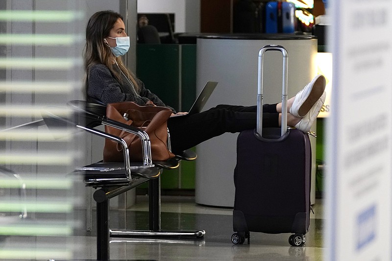 A traveler wears a mask as she waits for her flight in Terminal 3 at O'Hare International Airport in Chicago, Sunday, Nov. 29, 2020. Friday's total of new cases is the next-to-lowest daily number in the past 12 days, but Illinois state officials are bracing for another surge after many people around the country traveled for Thanksgiving and celebrated with family and friends. (AP Photo/Nam Y. Huh)