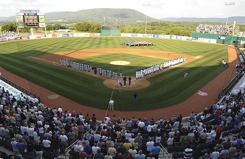 Teams line up along the baselines on June 20, 2006, during the playing of the national anthem before the first game in the inaugural season of the State College Spike baseball team in State College, Pa. Major League Baseball is creating a minor league for top eligible prospects leading to the summer draft., the league announced Monday. The founding members of the MLB Draft League are located in Ohio, Pennsylvania, West Virginia and New Jersey: the Mahoning Valley Scrappers, the State College Spikes, the Trenton Thunder, the West Virginia Black Bears and the Williamsport Crosscutters. - Photo by Pat Little of The Associated Press