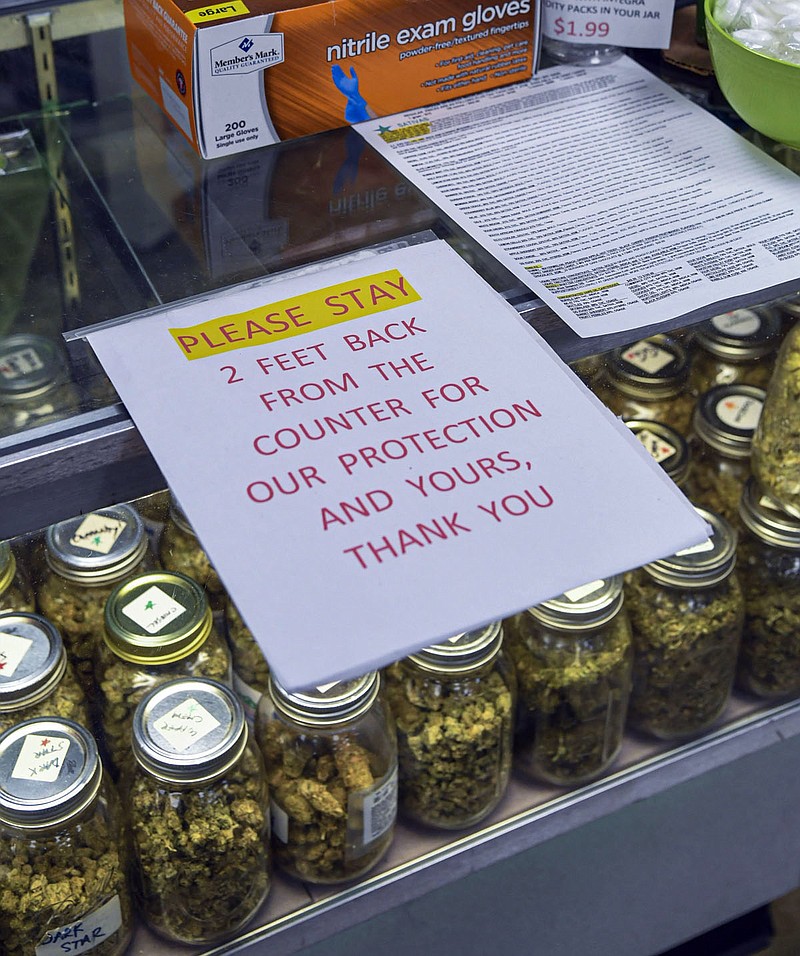 A sign at Green Springs Medical Marijuana Dispensary, 309 Seneca St., asks customers to keep a safe distance from the counter in March. -Photo by Grace Brown of The Sentinel-Record