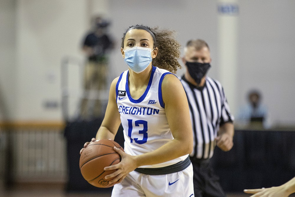 In this photo provided by Creighton Athletics, Creighton guard Rachael Saunders plays during a women's NCAA college basketball game against Drake in Omaha, Nebraska, on Wednesday, Nov. 25, 2020. Official Tom Danaher is at rear. The DePaul and Creighton women's basketball teams are among a few squads that have taken it a step further with their players wearing masks while on the court playing. (Catherine Grosdidier/Creighton Athletics via AP)