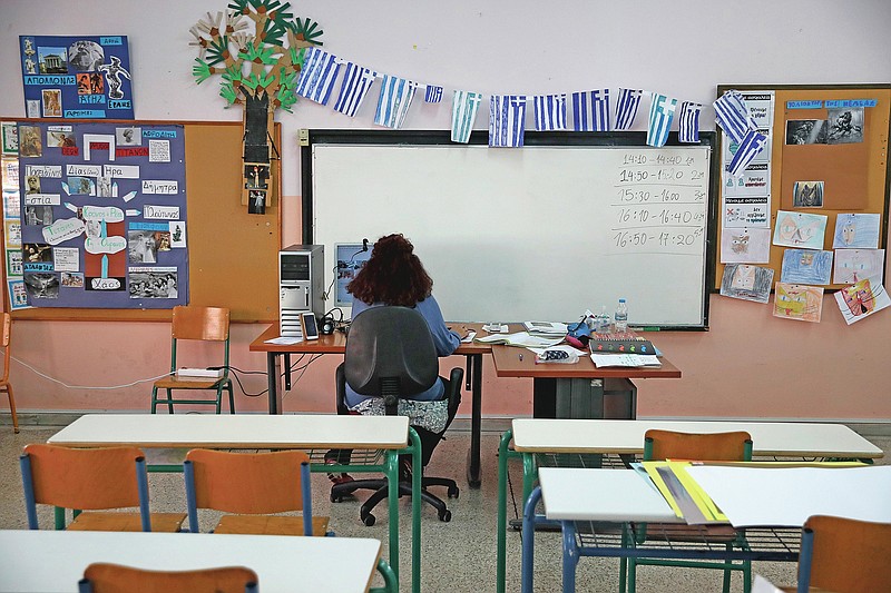 Teacher Katerina Papageorgiou gives an online lesson to C class students in an empty classroom of elementary school in Athens, Friday, Nov. 20, 2020. Most other European countries have vowed to keep schools open, but the pandemic has hit Greece hard for the first time in recent weeks following a successful lockdown in the spring, overwhelming hospitals in parts of the country. State television is making and broadcasting lessons, while teachers sit in empty classrooms talking to remote students. Despite some problems, they say it keeps children in touch with their schools. (AP Photo/Thanassis Stavrakis)