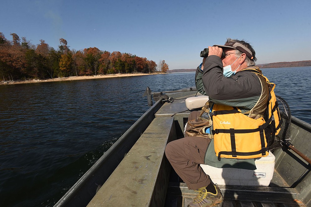 Joe Neal of Fayetteville looks for birds flying high Nov. 6 2020 over Beaver Lake. Neal looked for birds near Rocky Branch park, one of the top birding destinations on the lake. Neal found raptors, waterfowl and songbirds during a morning of birding by boat. Go to nwaonline.com/201208Daily/ to see more photos.
(NWA Democrat-Gazette/Flip Putthoff