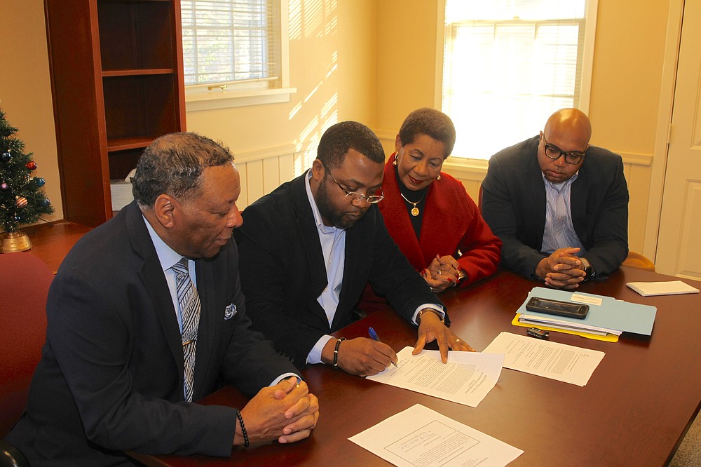 In this Dec. 23, 2019 file photo, Joseph McCorvey, left, looks on as Urban Renewal Agency Director Maurice Taggart signs papers officially transferring ownership of the Plaza Hotel to the city of Pine Bluff. Also looking on are Pine Bluff Mayor Shirley Washington and Go Forward Pine Bluff CEO Ryan Watley. (Arkansas Democrat-Gazette file photo)