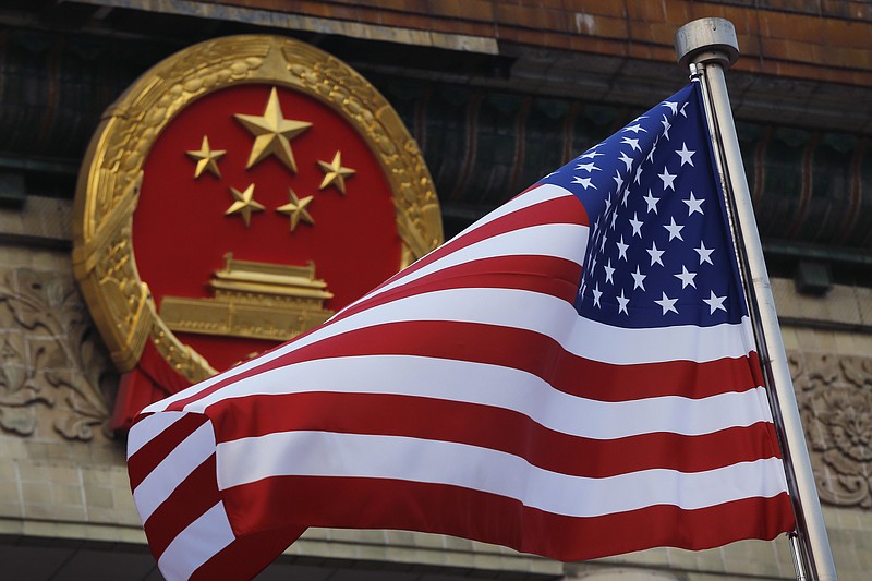 FILE - In this Nov. 9, 2017, file photo, an American flag is flown next to the Chinese national emblem during a welcome ceremony for visiting U.S. President Donald Trump outside the Great Hall of the People in Beijing. U.S. and Chinese trade envoys discussed strengthening coordination of their government’s economic policies during a phone meeting, the Ministry of Commerce announced. (AP Photo/Andy Wong, File)