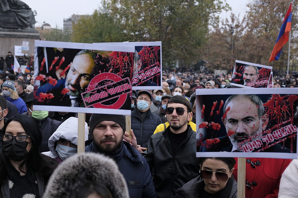 Opposition demonstrators hold posters of Armenian Prime Minister Nikol Pashinyan painted in red to represent the blood of those killed during the conflict Armenian soldiers and civilians as they attend a rally to pressure him to resign over a peace deal with neighboring Azerbaijan in Republic Square in Yerevan, Armenia, Saturday, Dec. 5, 2020. Tens of thousands of opposition supporters marched across the Armenian capital Saturday to push for the resignation of the ex-Soviet nation's prime minister over his handling of the conflict with Azerbaijan over Nagorno-Karabakh. (Hrant Khachatryan /PAN Photo via AP)