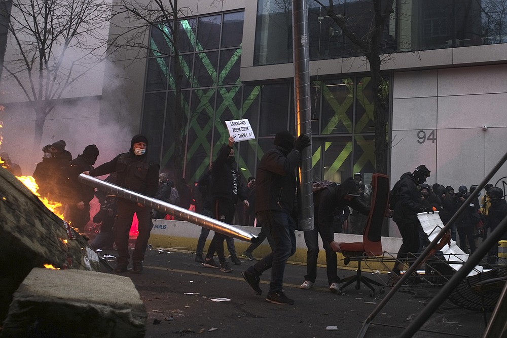 Youths set up a barricade during a demonstration Saturday, Dec. 5, 2020 in Paris. Thousands marched in protests around France on Saturday against a contested security bill with tensions quickly rising at the Paris march as intruders set fire to several cars, broke windows and tossed projectiles at police. (AP Photo/Lewis Joly)